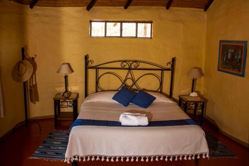 a bedroom with a large bed with blue pillows at Hotel Valle Místico in Tepoztlán