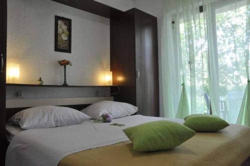 a bedroom with a large bed with green pillows at Apartment Peace in Rab