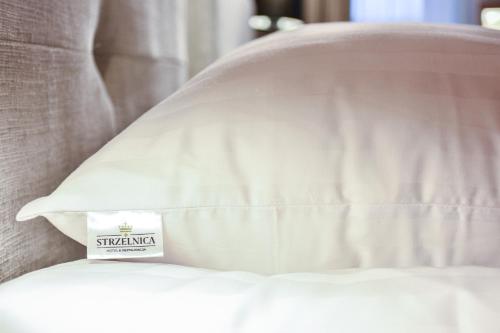a pillow with a sign on it sitting on a bed at Strzelnica Hotel i Restauracja in Starogard Gdański