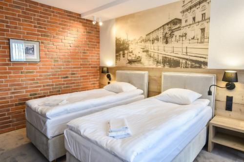 three beds in a room with a brick wall at Strzelnica Hotel i Restauracja in Starogard Gdański
