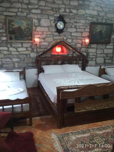a bedroom with two beds and a stone wall at Karafil Guesthouse in Gjirokastër