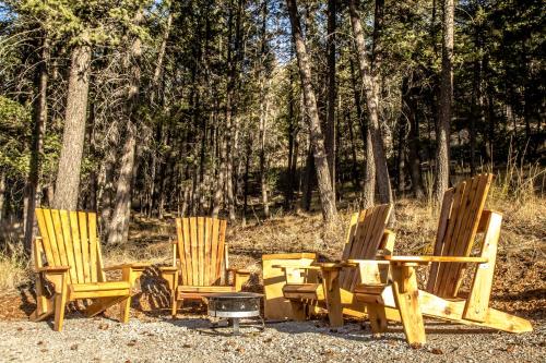 four wooden chairs and a grill in the woods at Gateway Motel in Radium Hot Springs