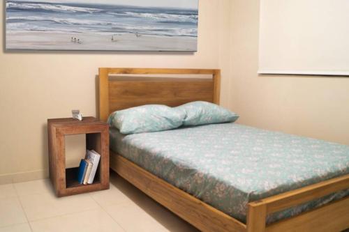 a bedroom with a bed with a wooden frame and a table at Chipipe Salinas Beachfront Apartment w Parking in Salinas