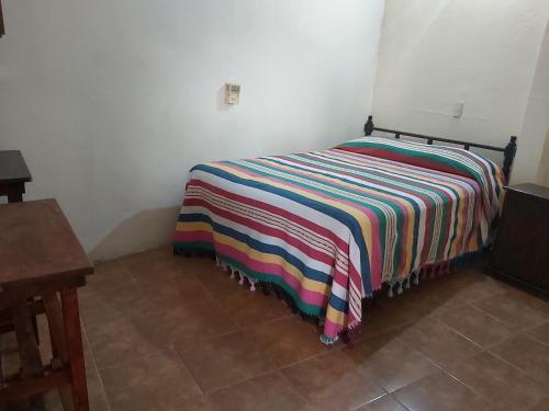 a bed with a blanket and pillows on top of it at Hotel Posada Playa Manzanillo in Puerto Escondido