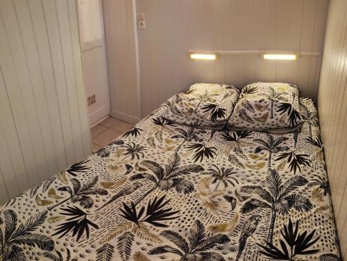 a bedroom with a bed with a black and white comforter at Le Crotoy Plage Baie de somme Appt l'Aigrette in Le Crotoy