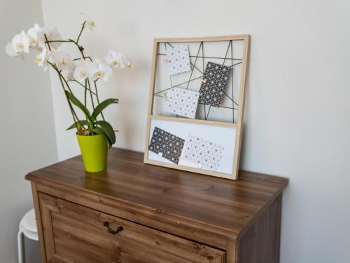 a vase of flowers on a wooden dresser with a mirror at Zakątek Zator 2 by Housine in Zator