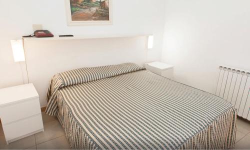a small bedroom with a bed with a striped blanket at Hotel Castiglione in Ischia