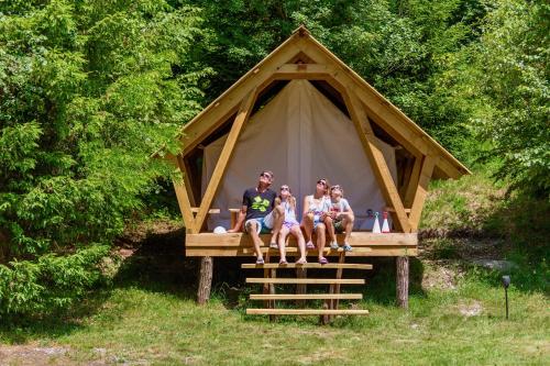 
people are sitting on a wooden bench at Adrenaline Check Camping in Bovec
