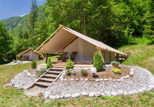 ein Zelt auf einem Feld mit Felsen und Bäumen in der Unterkunft Adrenaline Check Camping in Bovec