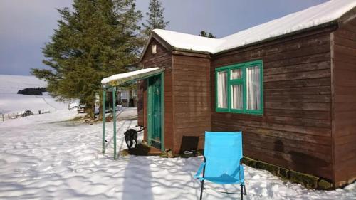 a house with a blue chair in the snow at Scotland Shooting Club in Balintore