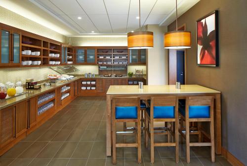 a kitchen with wooden cabinets and a island with stools at Hyatt Place Lansing-East in Lansing