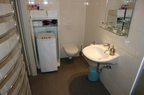 biała łazienka z umywalką i toaletą w obiekcie Holiday Home Roy w Berlinie