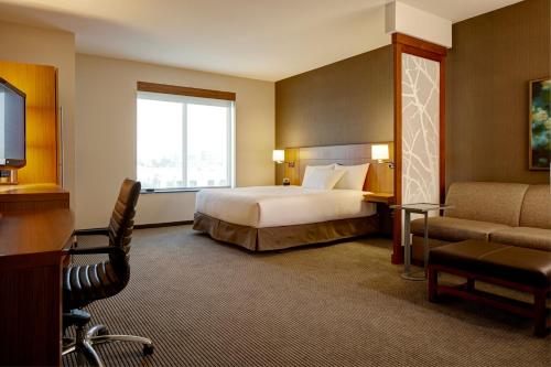 a large hotel room with a bed and a window at Hyatt Place Lansing-East in Lansing