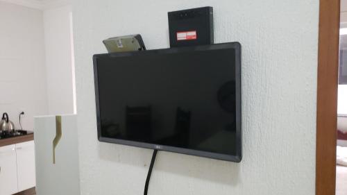TV de pantalla plana colgada en la pared en Apartamento novo 450 mt da praia Ingleses, en Florianópolis