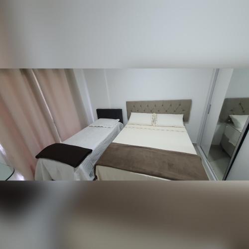 a small room with two beds and a mirror at Village AREIAS ITACIMIRIM - PÉ NA AREIA in Itacimirim
