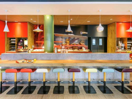 a restaurant with a bar with colorful stools at ibis Hotel Hannover City in Hannover