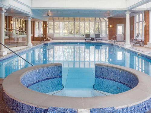 een groot zwembad met blauw water in een gebouw bij Mercure Blackburn Dunkenhalgh Hotel & Spa in Accrington