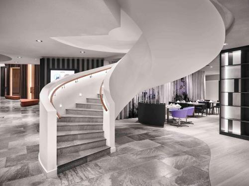 a spiral staircase in a lobby with tables and chairs at Novotel Moscow Kievskaya in Moscow