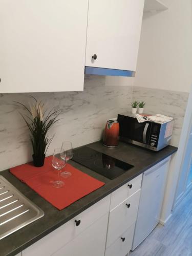 eine Küche mit einer Theke mit einer Mikrowelle und Weingläsern in der Unterkunft BK City Apartments in Backnang