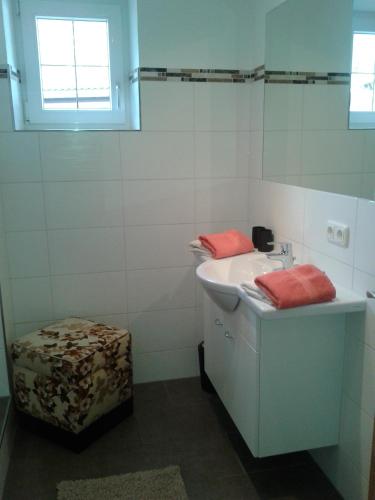 a white bathroom with a sink and a stool at Gästehaus Hosp in Reutte