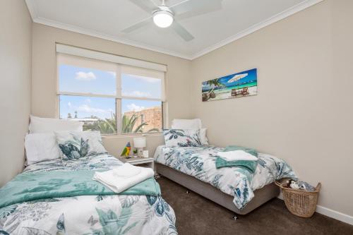 1 dormitorio con 2 camas y ventana en Beach Haven on The Hill, en Newcastle