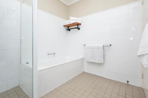 a white bathroom with a shower and a tub at Beach Haven on The Hill in Newcastle