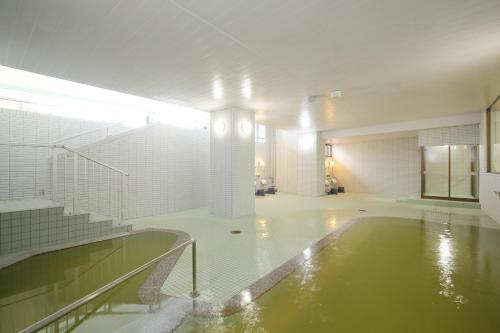 een groot zwembad in een gebouw met een bad bij Toya-onsen Hotel Hanabi in Lake Toya