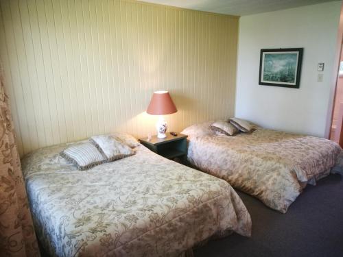 a hotel room with two beds and a lamp on a table at Auberge La Coudriere (Cool Hotel) in L'Isle-aux-Coudres