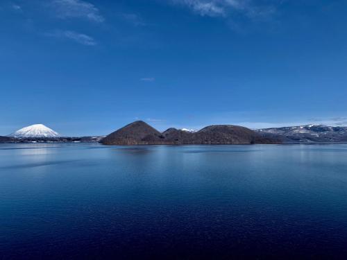 a large body of water with a mountain in the background at Toya-onsen Hotel Hanabi in Lake Toya