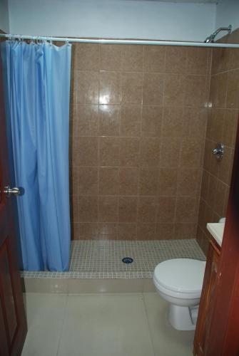 a bathroom with a toilet and a blue shower curtain at Hotel Coastalbay 2 & Golf Cart Rental in San Pedro