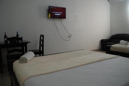 a room with a bed and a tv on the wall at Hotel Coastalbay 2 & Golf Cart Rental in San Pedro