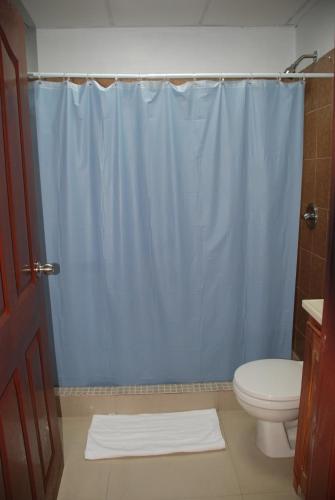 a bathroom with a blue shower curtain and a toilet at Hotel Coastalbay 2 & Golf Cart Rental in San Pedro