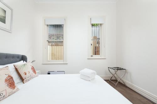 een witte slaapkamer met een bed en 2 ramen bij STUNNING SYDNEY HOME 1 in Sydney