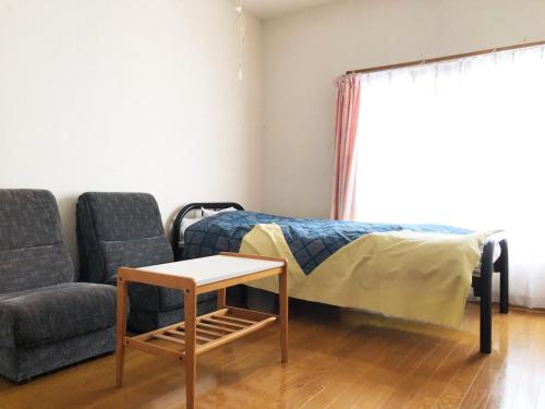 um quarto com uma cama, um sofá e uma mesa em 旅館FURUYA em Hakuba