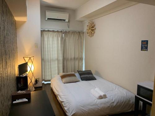 een slaapkamer met een bed met witte lakens en een raam bij Exsaison Shirokita 410 in Osaka