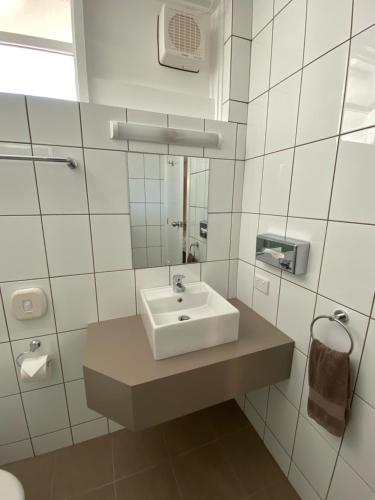 Baño blanco con lavabo y espejo en Warrina Motor Inn Wodonga CBD, en Wodonga