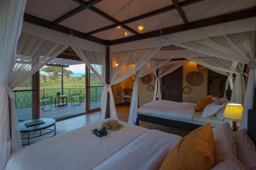 a bedroom with two beds and a balcony at Serengeti Sametu Camp in Serengeti National Park