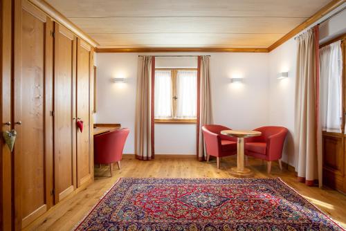 a room with red chairs and a table and a rug at Hotel Natale in Cortina dʼAmpezzo