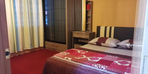 1 dormitorio con 1 cama con edredón en Aqiza Home Kuala Krai, en Kuala Kerai
