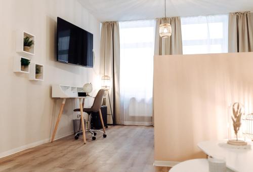ein Wohnzimmer mit einem Schreibtisch und einem TV im Zimmer in der Unterkunft Apartment an der Altstadt (#7) in Hameln
