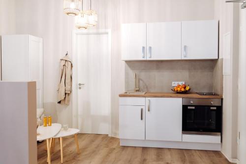 een keuken met witte kasten en een tafel met een fruitschaal bij Apartment an der Altstadt (#7) in Hameln