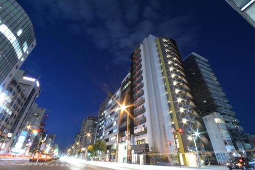 LUXCARE HOTEL في أوساكا: شارع المدينة بالليل فيه مباني وانوار الشارع