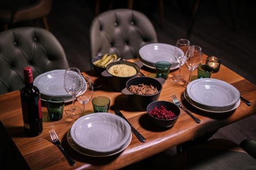 a wooden table with plates and wine glasses and food at Levi Black Apartments in Levi