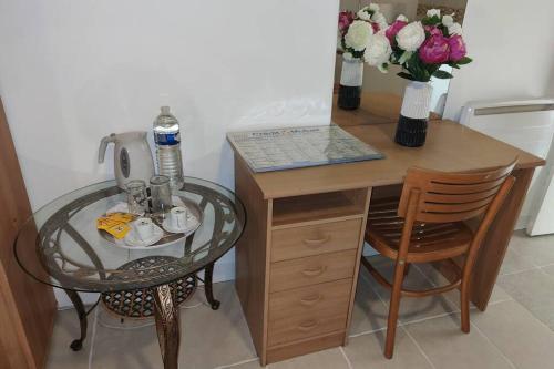 een klein bureau met een glazen tafel en een tafel met bloemen bij Charmant studio - Ref KP in Montfermeil