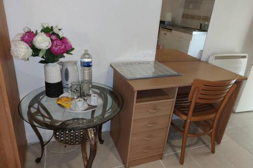 een kleine tafel met een vaas met bloemen en een tafel met een glazen tafel bij Charmant studio - Ref KP in Montfermeil