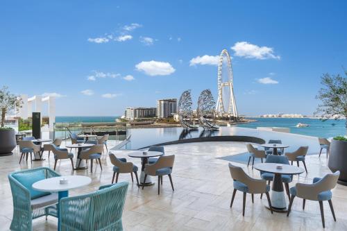 a restaurant with tables and chairs and a ferris wheel in the background at Address Beach Resort in Dubai