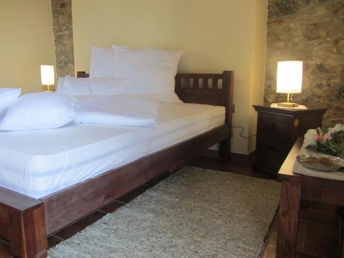 a bedroom with a bed with white sheets and pillows at Tenuta Seripa in Sassetta