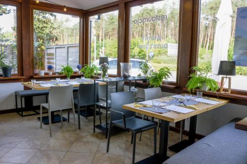 uma sala de jantar com mesas, cadeiras e janelas em Restauracja & Hotel Punkt Widzenia em Skórzewo