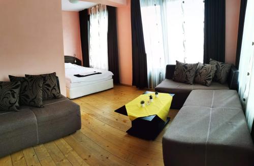 a living room with two couches and a yellow table at Apartments Black Horse in Pamporovo