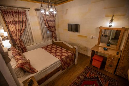 a small bedroom with a bed and a mirror at Göreme Reva Hotel in Goreme